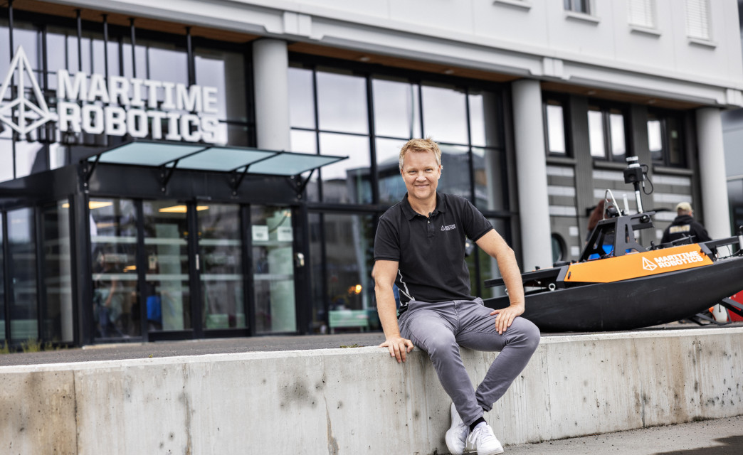 The CEO of Maritime Robotics seated in front of the Trondheim offices, accompanied by an Otter Unmanned Surface Vehicle (USV).