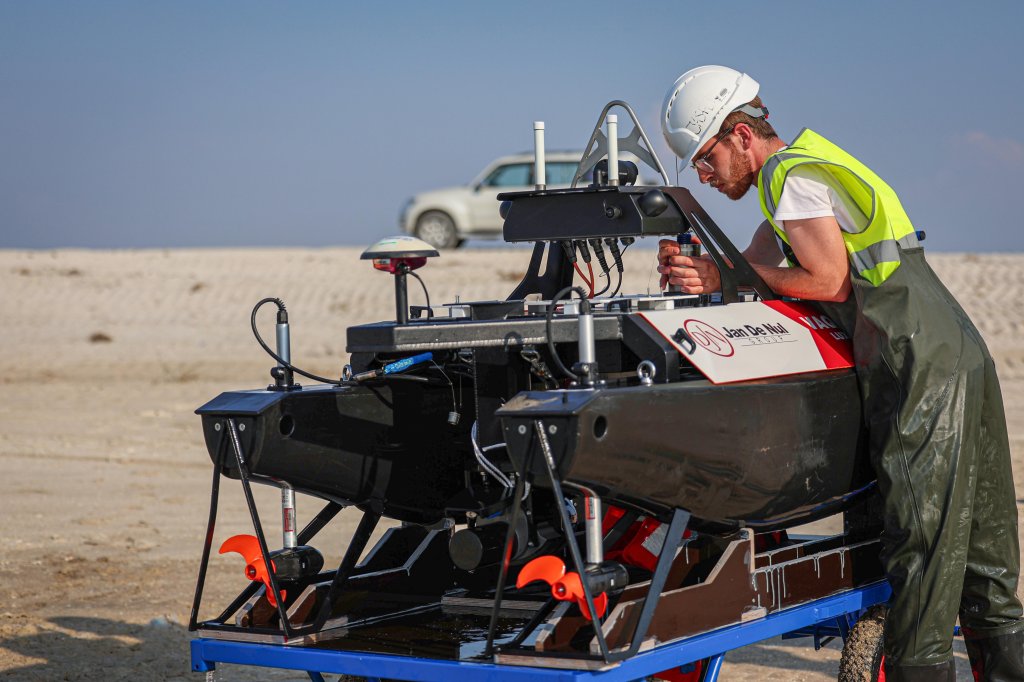 A person in a white helmet and safety vest working on a USV vessel.