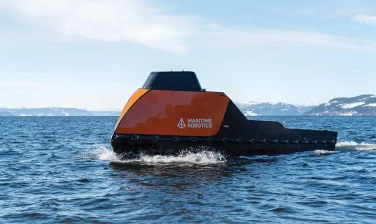 Side view of an orange-colored Mariner X USV in the open ocean.