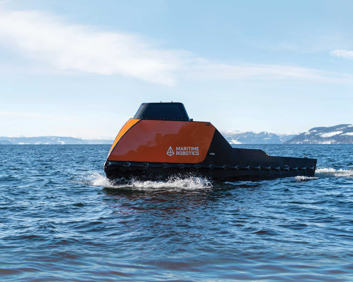 Side view of an orange-colored Mariner X USV in the open ocean.