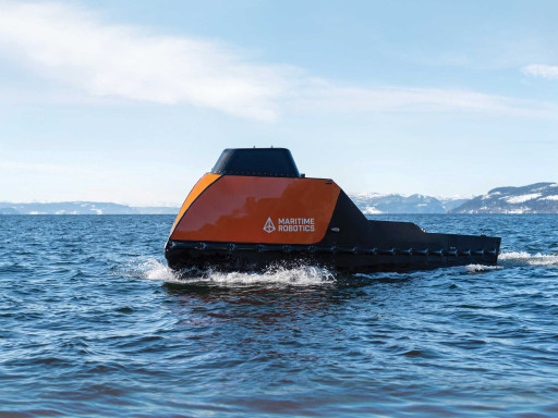 Side view of an orange-colored Mariner X USV in the open ocean.