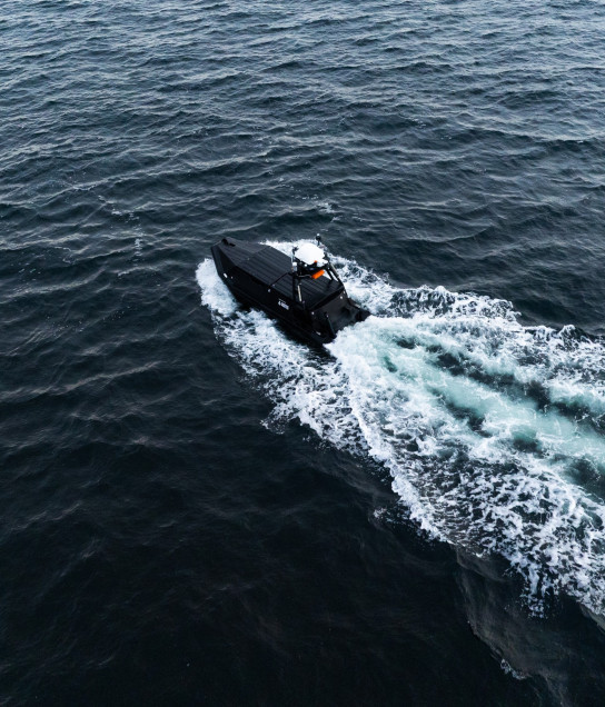 Aerial view of the Mariner USV cruising autonomously through open ocean waters, leaving a visible water trace.