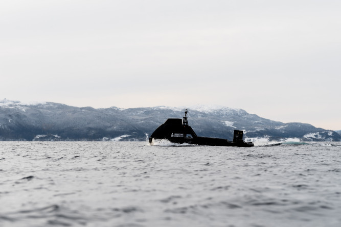 Side view of the Mariner X autonomous vessel navigating Norwegian waters with mountains in the background.