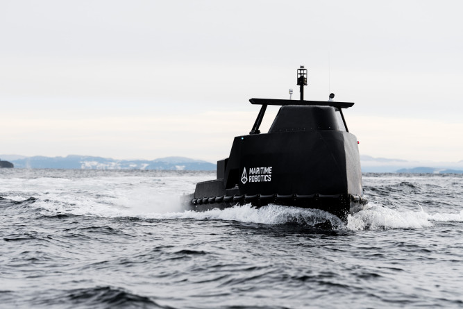 Perspective view of the Mariner X USV navigating across open water with its communication and sensor systems visible.